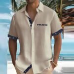 Mann in beiger Sommerhemd mit blauem Muster, steht am Strand vor Palmen und Meer. Perfekte Strandmode, lässiger Urlaubslook.